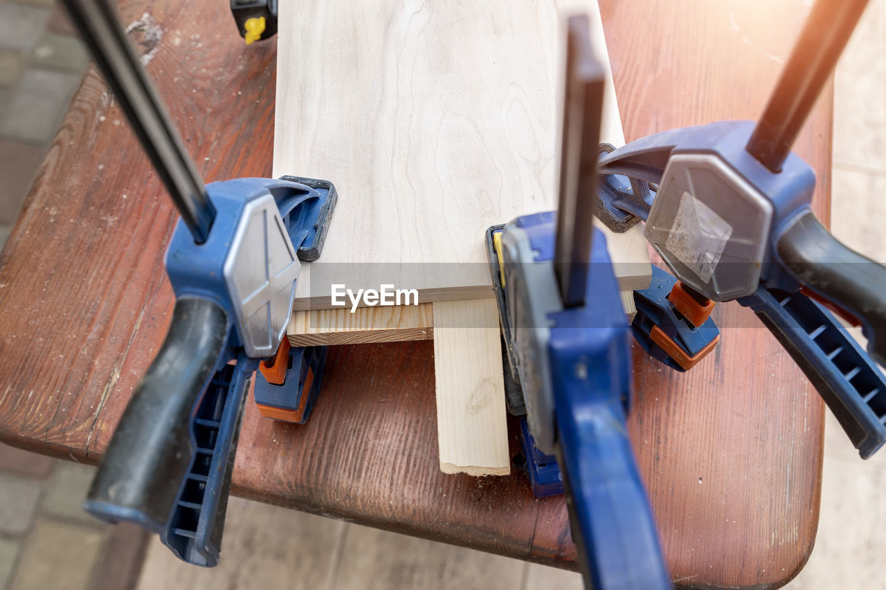 work tool, wood, tool, hand tool, indoors, equipment, carpentry, blue, industry, drill, workshop, hammer, workbench, no people, construction industry, diy, flooring, high angle view, carpenter, occupation, hand saw, business, working