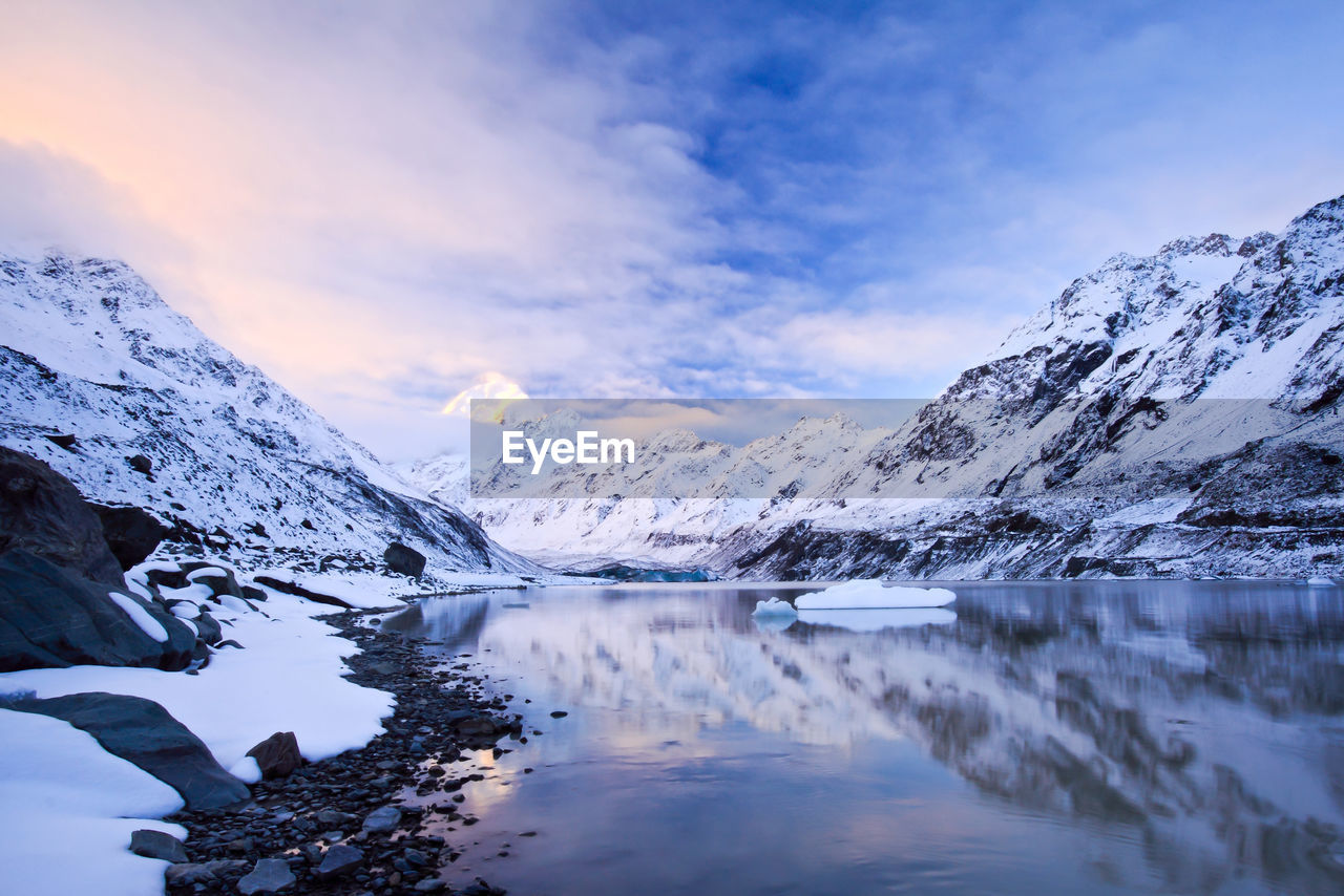 Snowcapped mountain range against cloudy sky