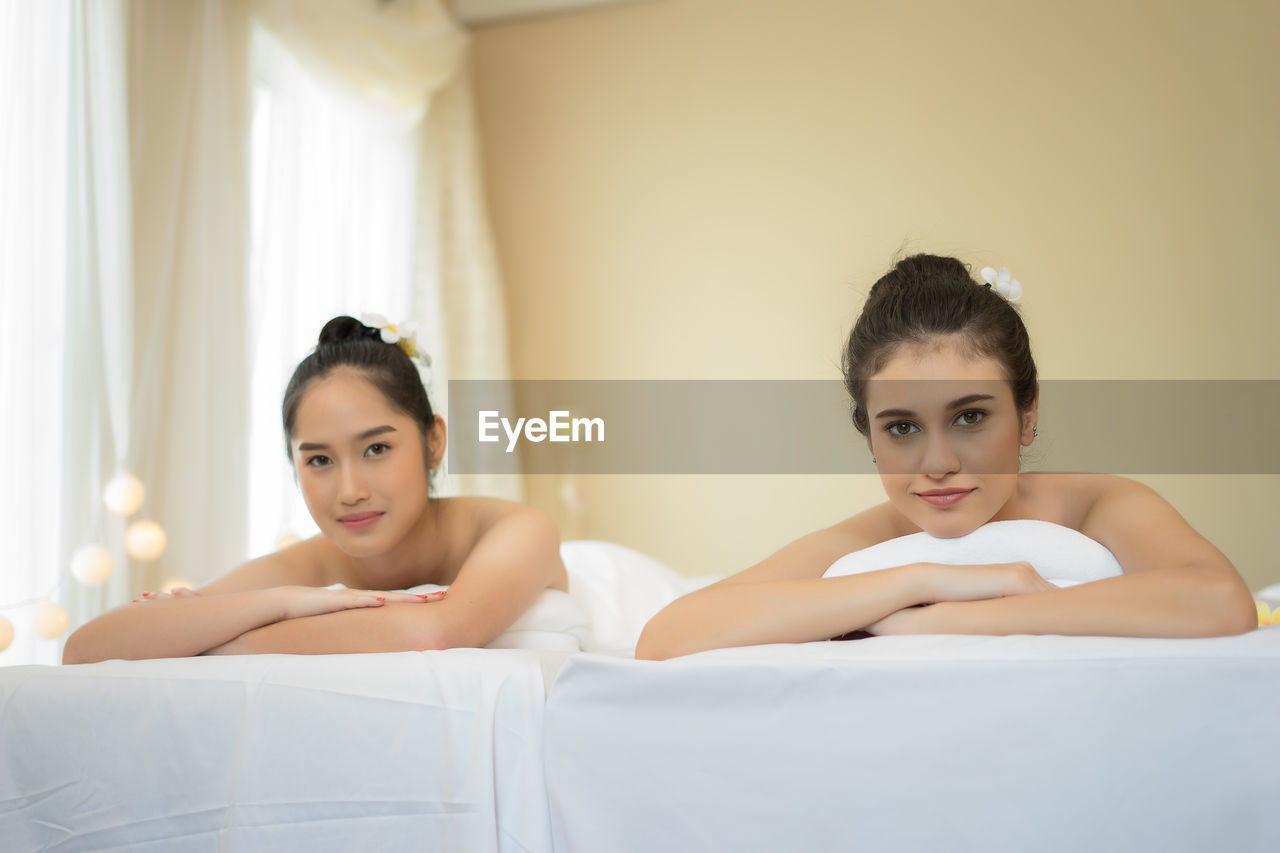 Young female friends lying on massage tables in spa