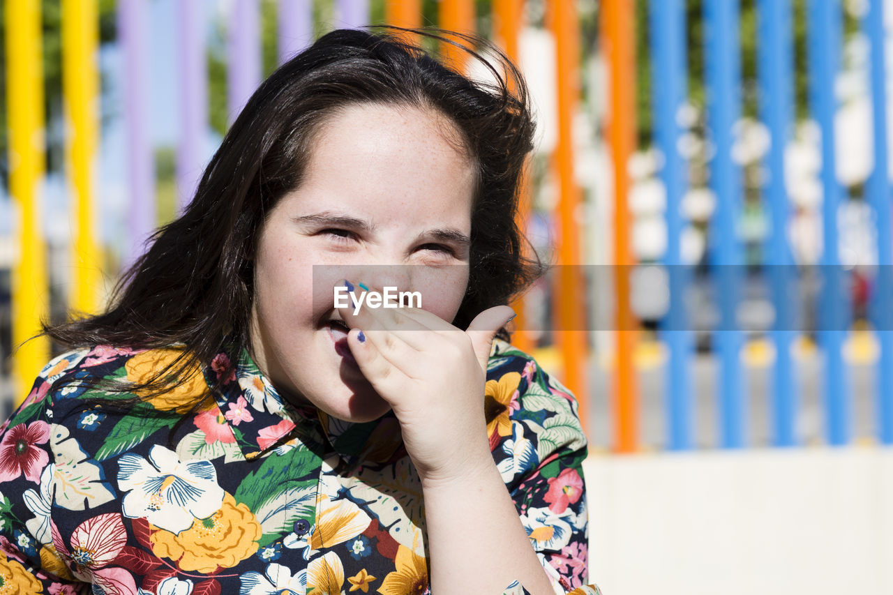 Teenager girl with down syndrome laughing, hand covering mouth