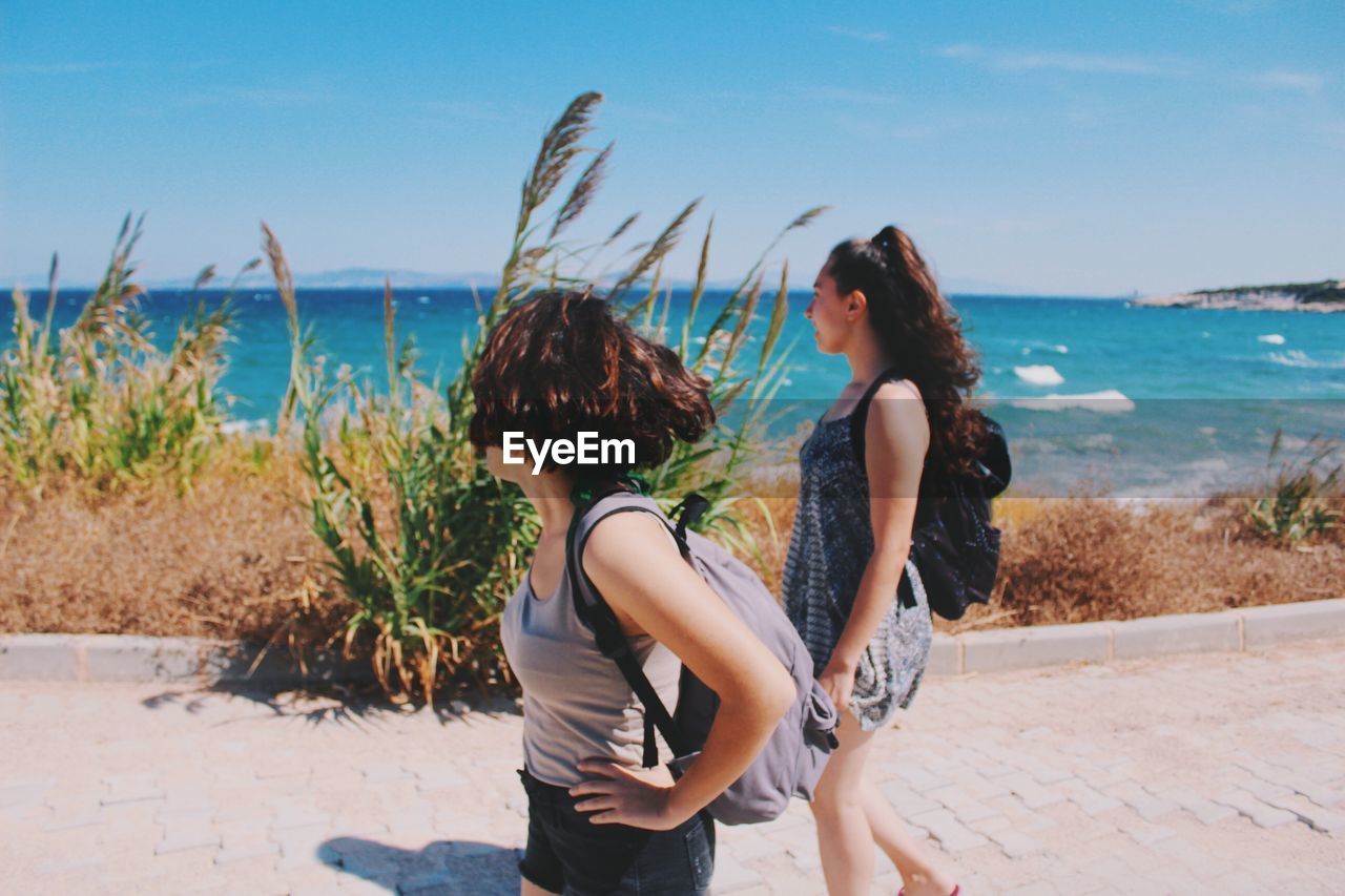 Young women walking on promenade against sky