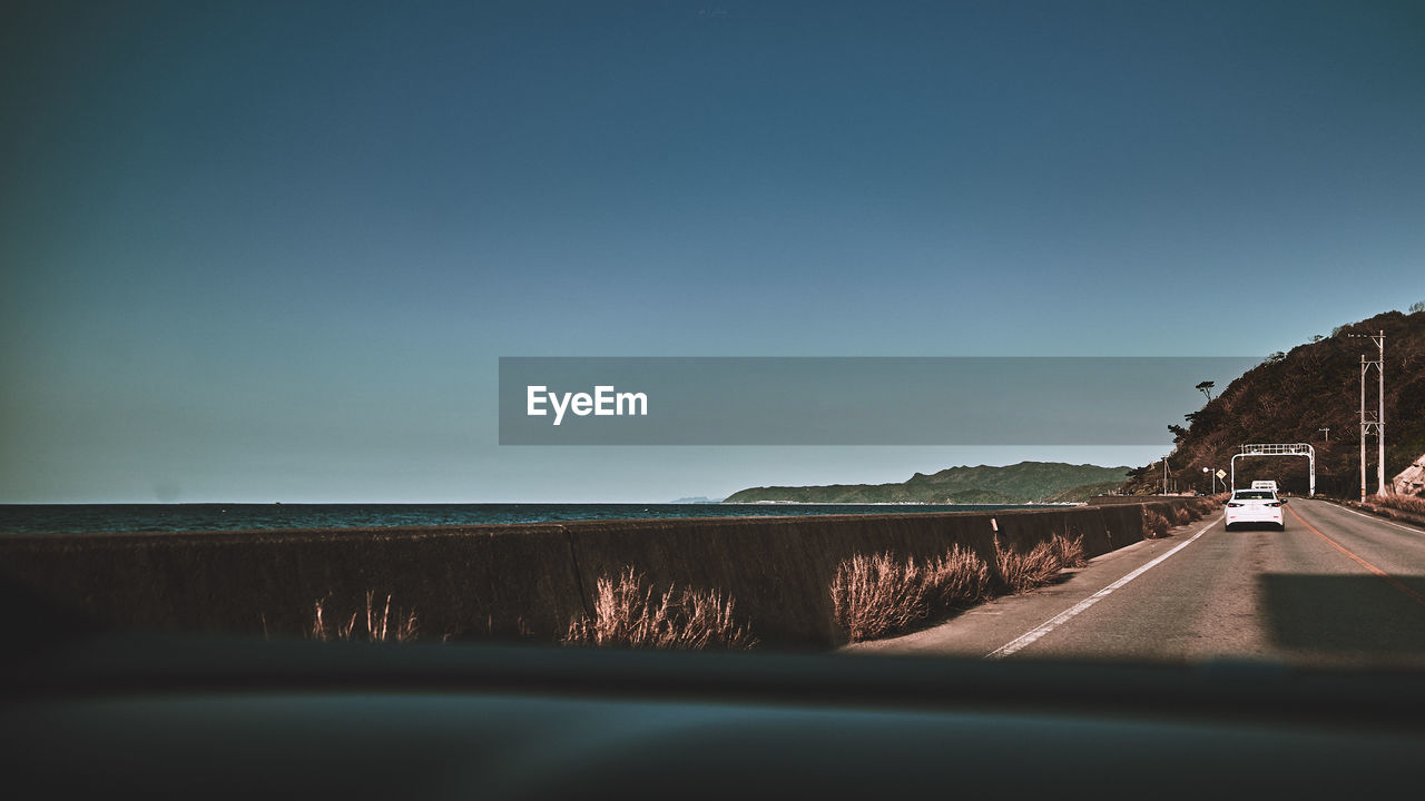 ROAD SEEN THROUGH CAR WINDSHIELD