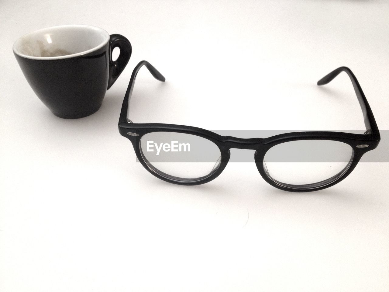 Close-up of eyeglasses with coffee cup on table