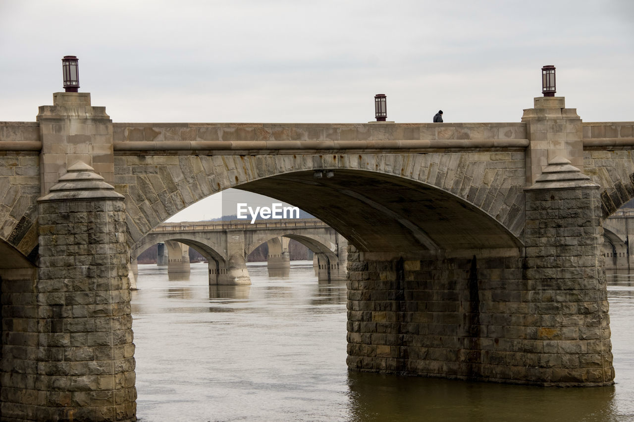 Arch bridge over river against sky