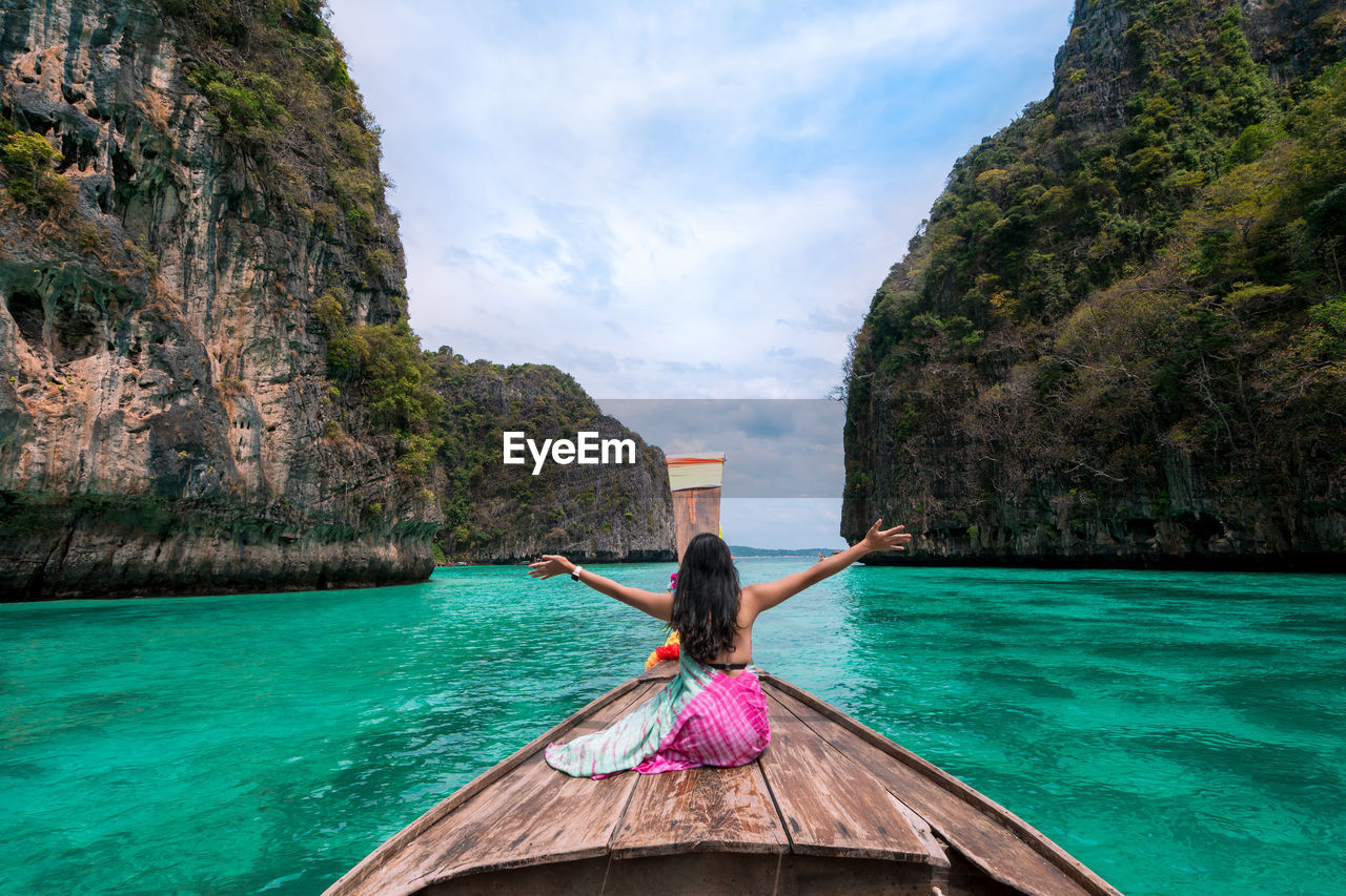 rear view of man kayaking in sea against mountain