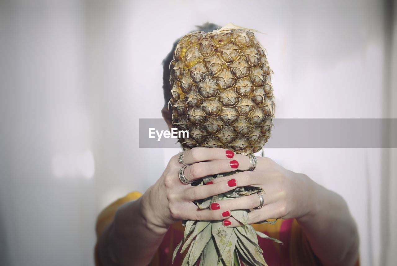 Woman holding pineapple in front of face