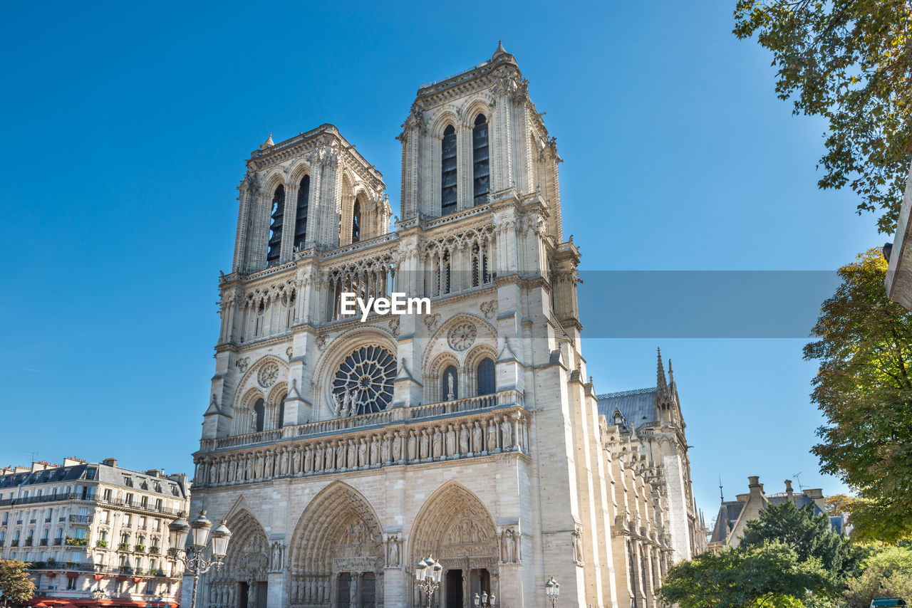 Notre dame de paris - people at famous cathedral with sun and blue sky before fire april 15, 2019