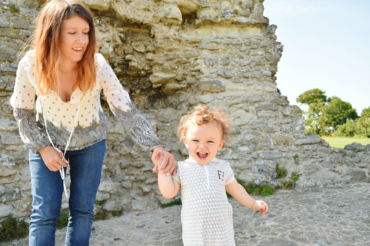 Smiling mother holding toddler boy against hadleigh castle