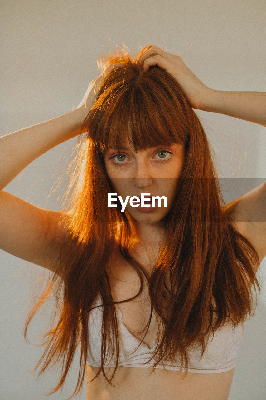 Portrait of young woman looking away against wall