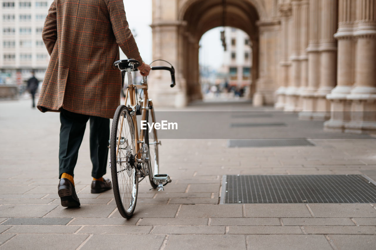 Midsection close up leg shot of a businessman with bicycle commuting to the office. historical area