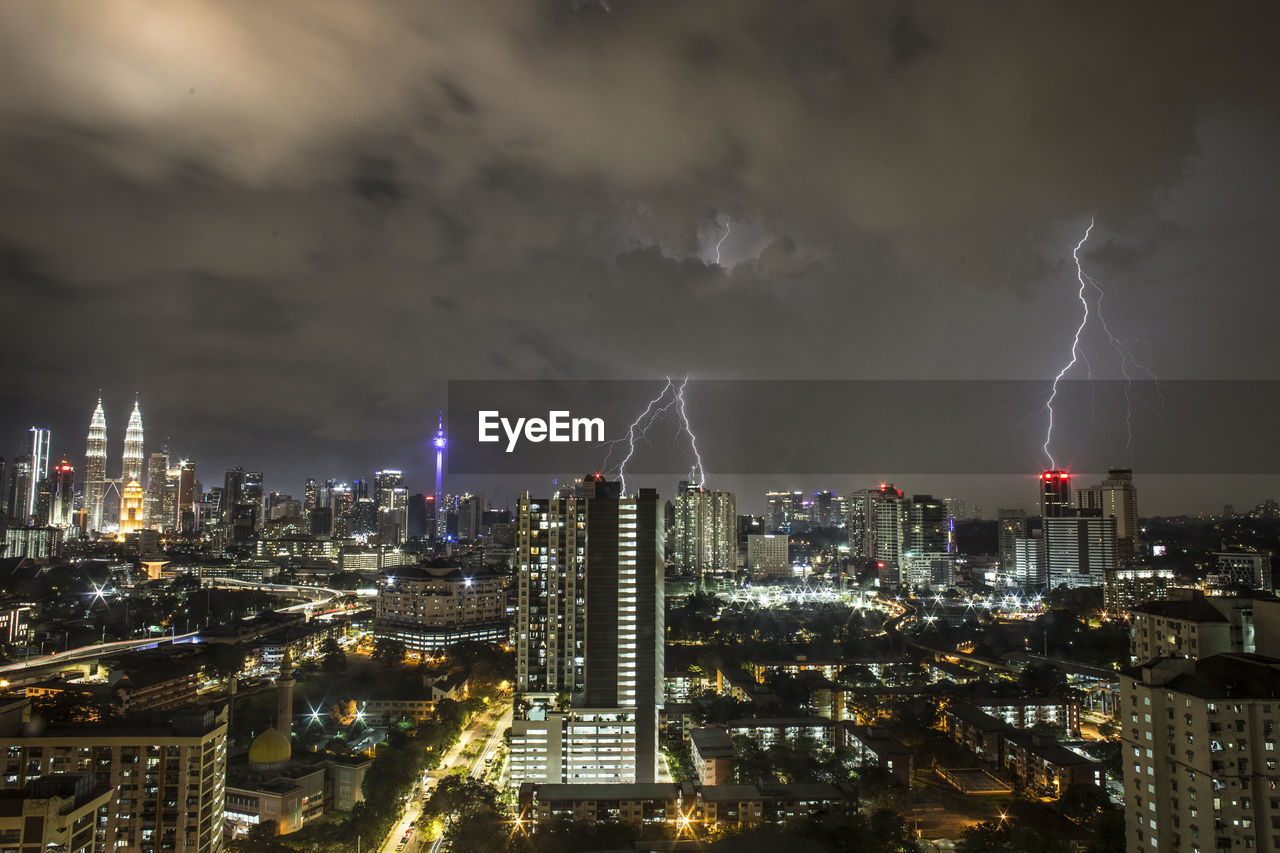 Lightning over illuminated cityscape at night