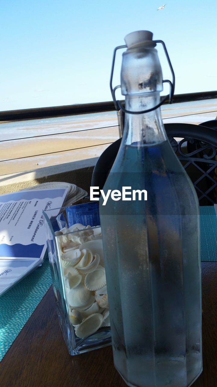 CLOSE-UP OF WATER IN GLASS BOTTLE ON TABLE