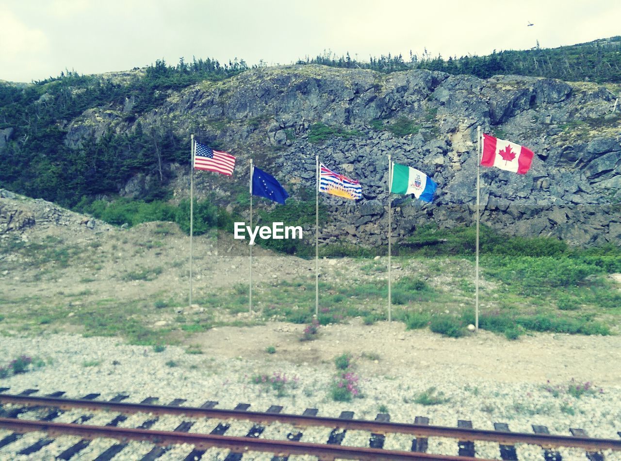 National flags waving against rocky mountains