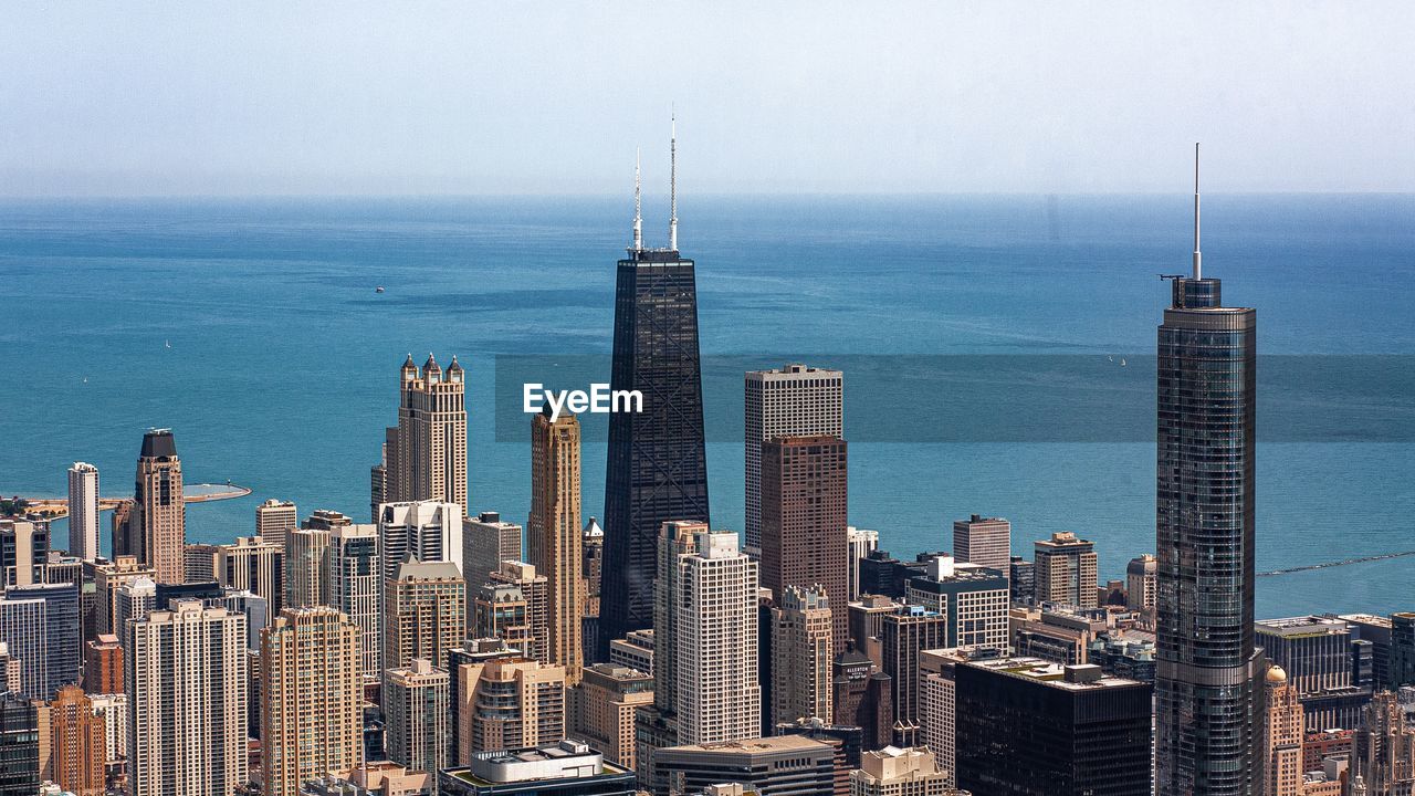 High angle view of modern buildings in city by sea