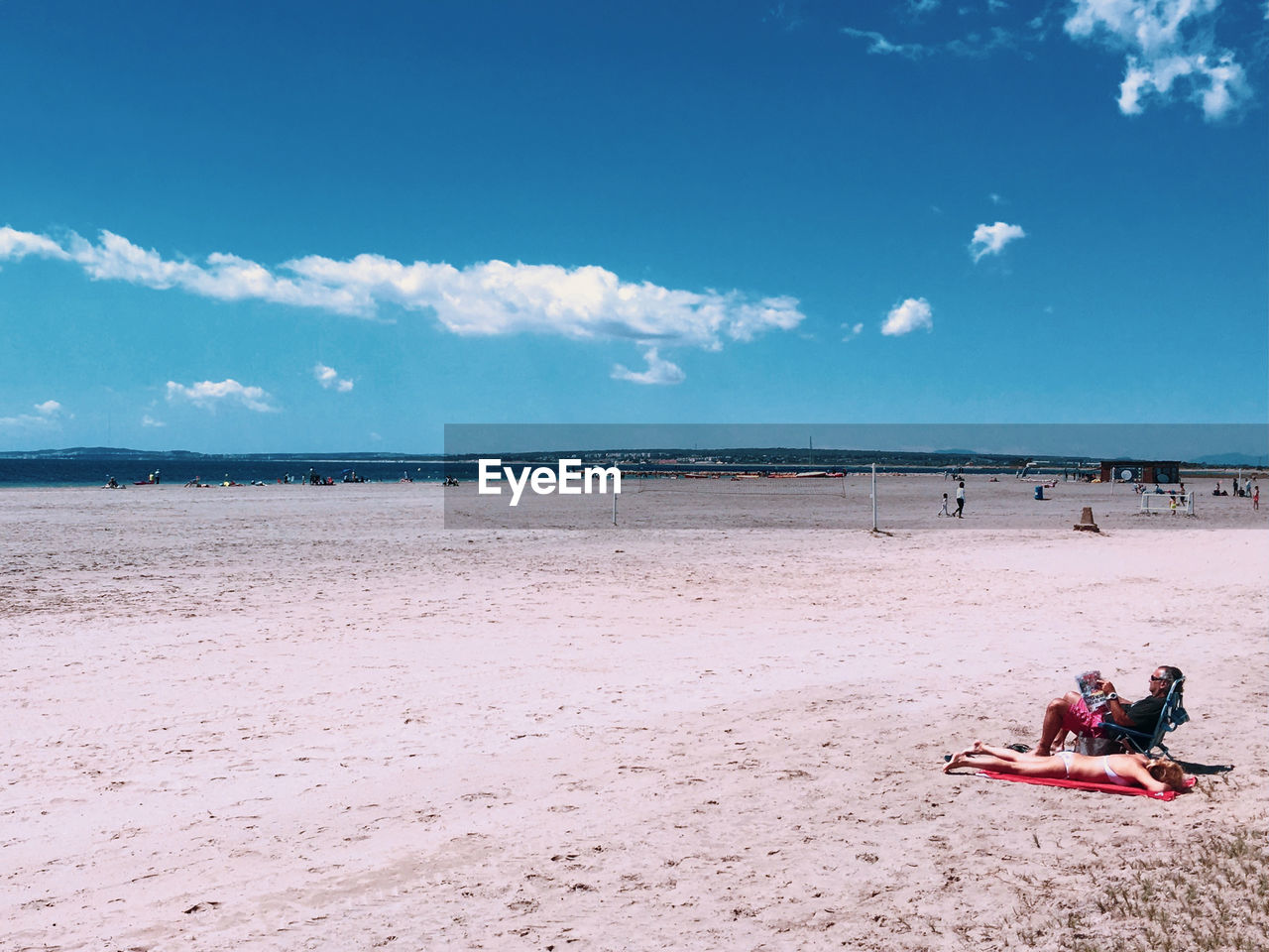 People relaxing on beach against sky