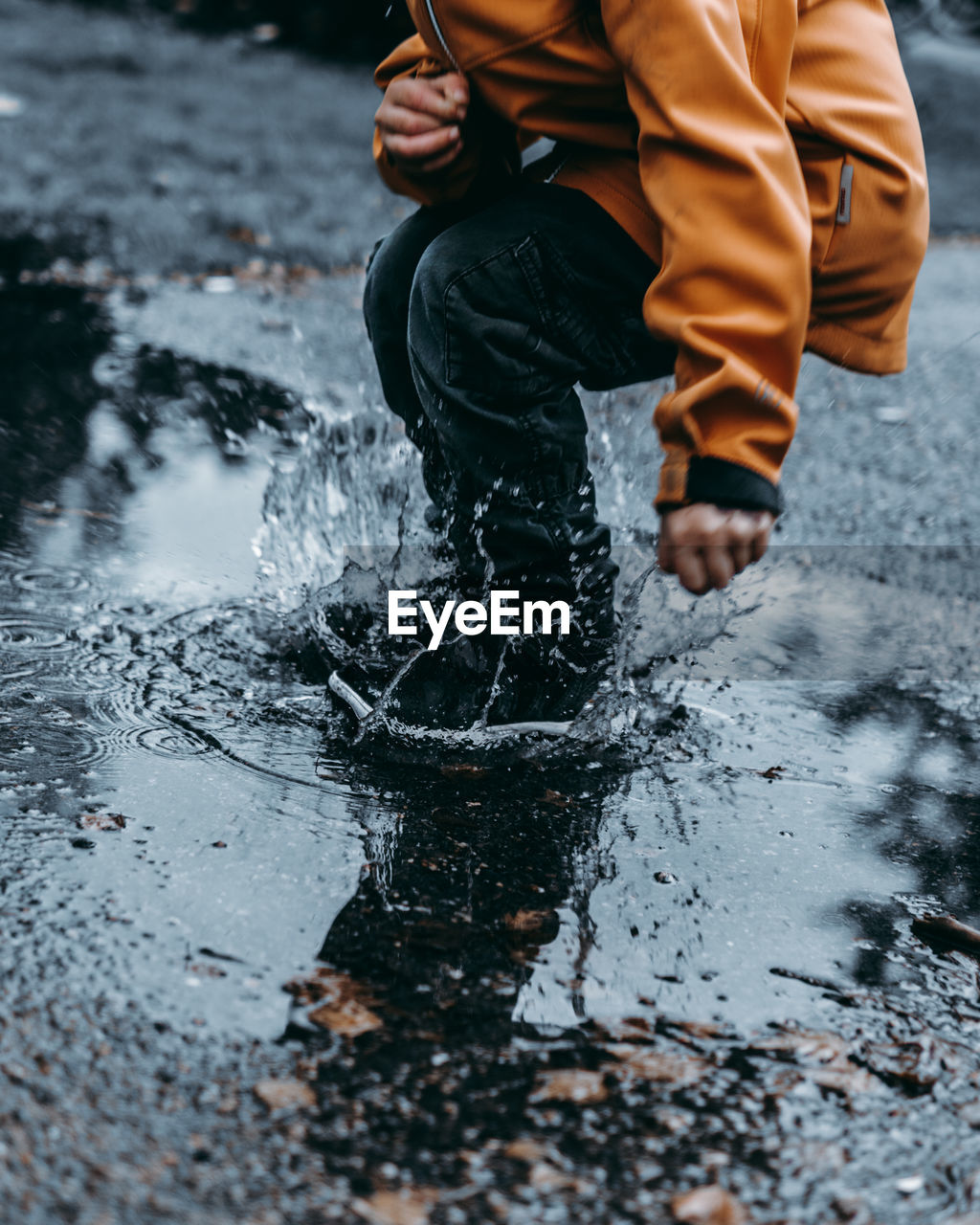 Low section of man jumping on puddle