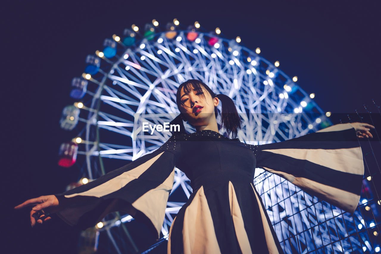 arts culture and entertainment, amusement park ride, amusement park, one person, adult, ferris wheel, night, young adult, illuminated, motion, person, emotion, happiness, clothing, low angle view, performance, musical theatre, portrait