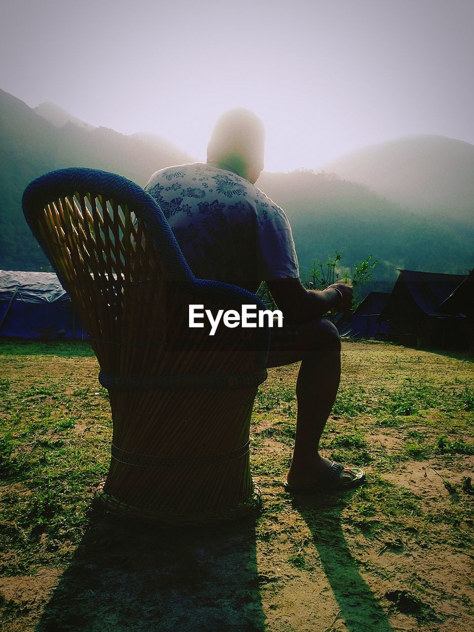 REAR VIEW OF MAN STANDING ON MOUNTAIN AGAINST CLEAR SKY