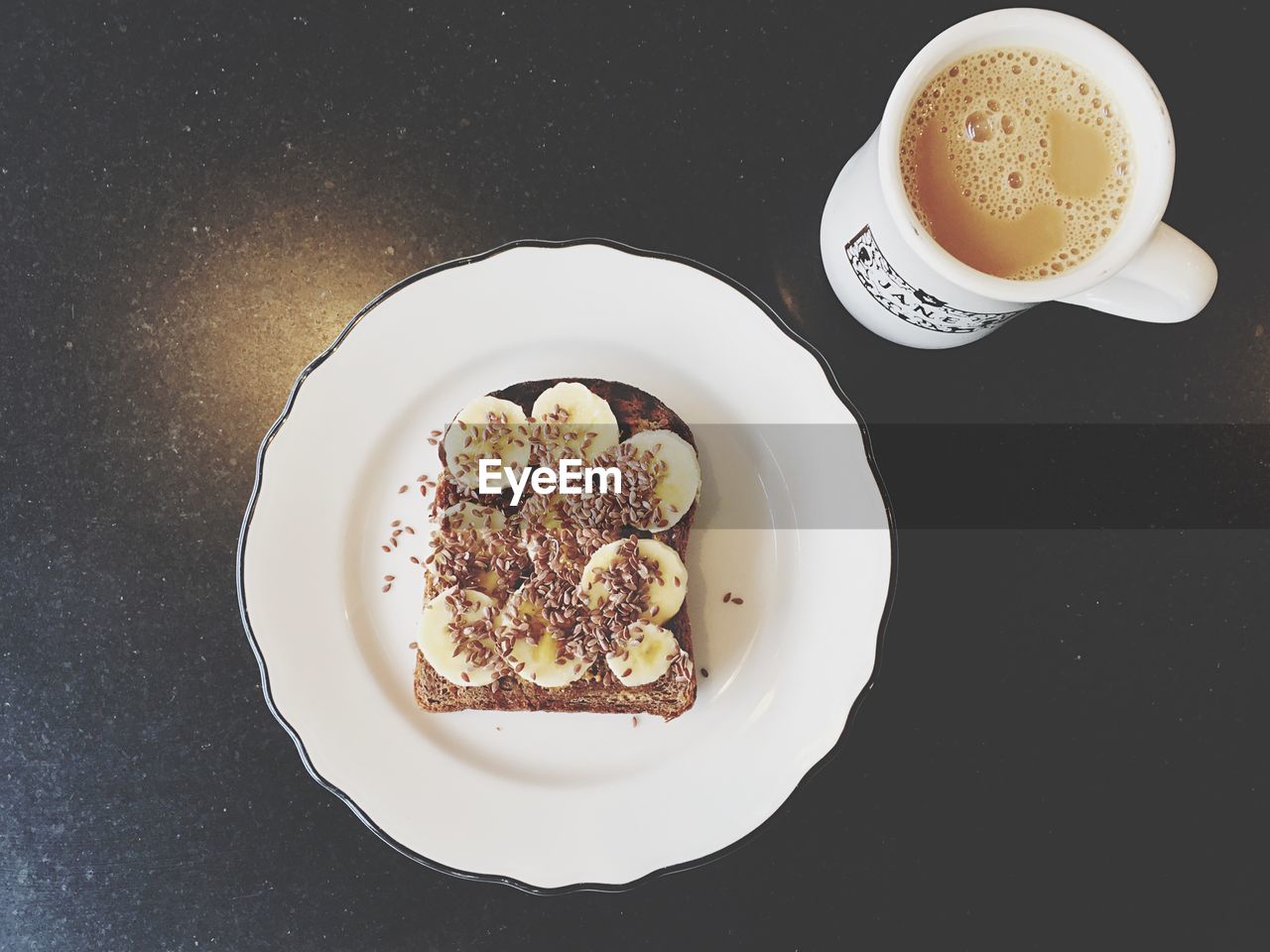 High angle view of flax seeds and banana slices by coffee cup on table