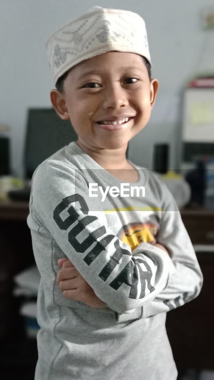 PORTRAIT OF SMILING BOY STANDING AT HOME