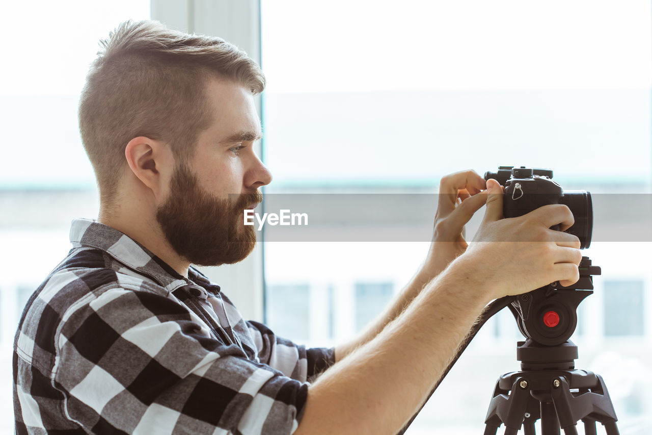 Profile view of man holding camera indoors