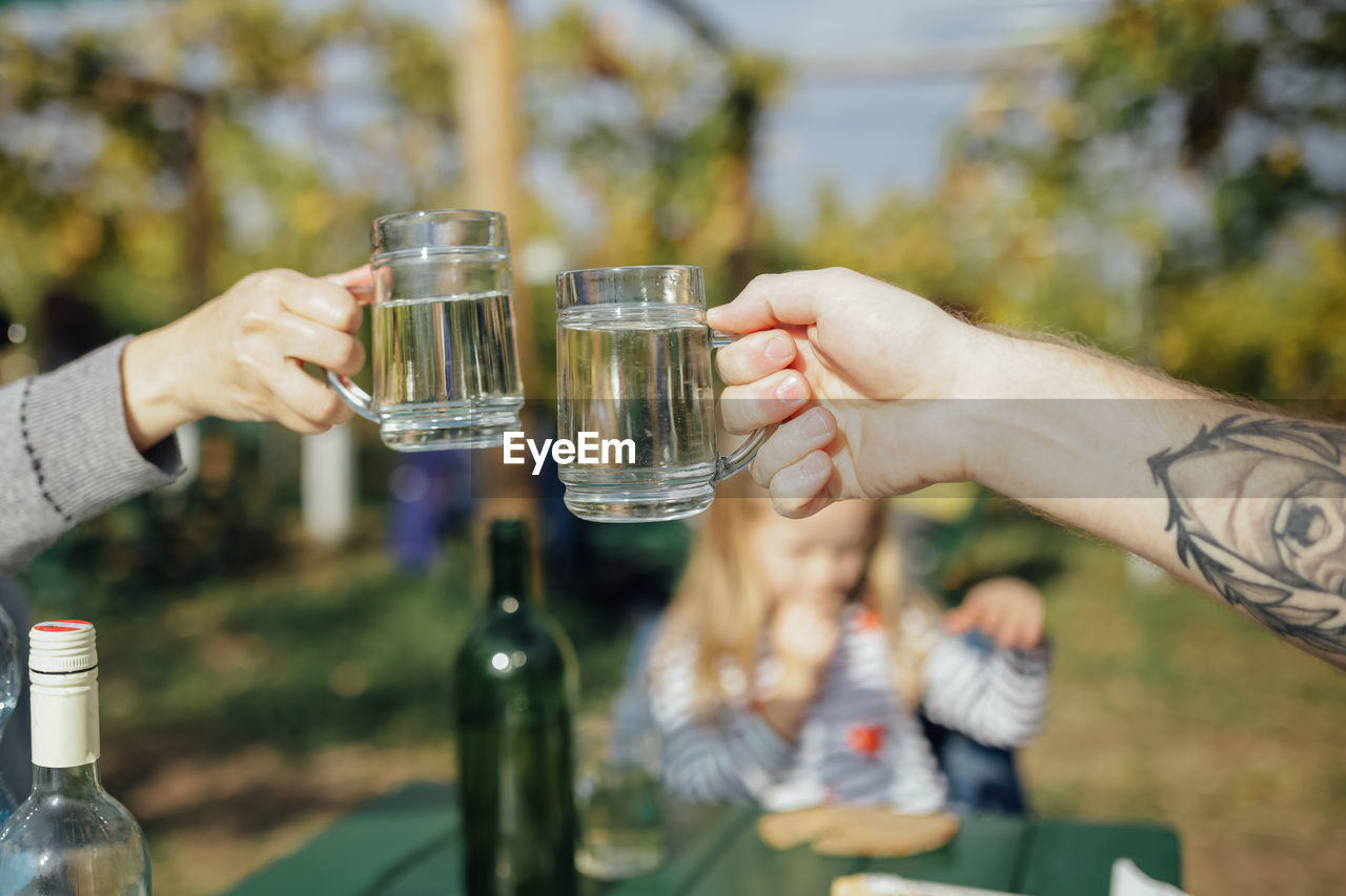Cropped hands of people toasting drinks at backyard