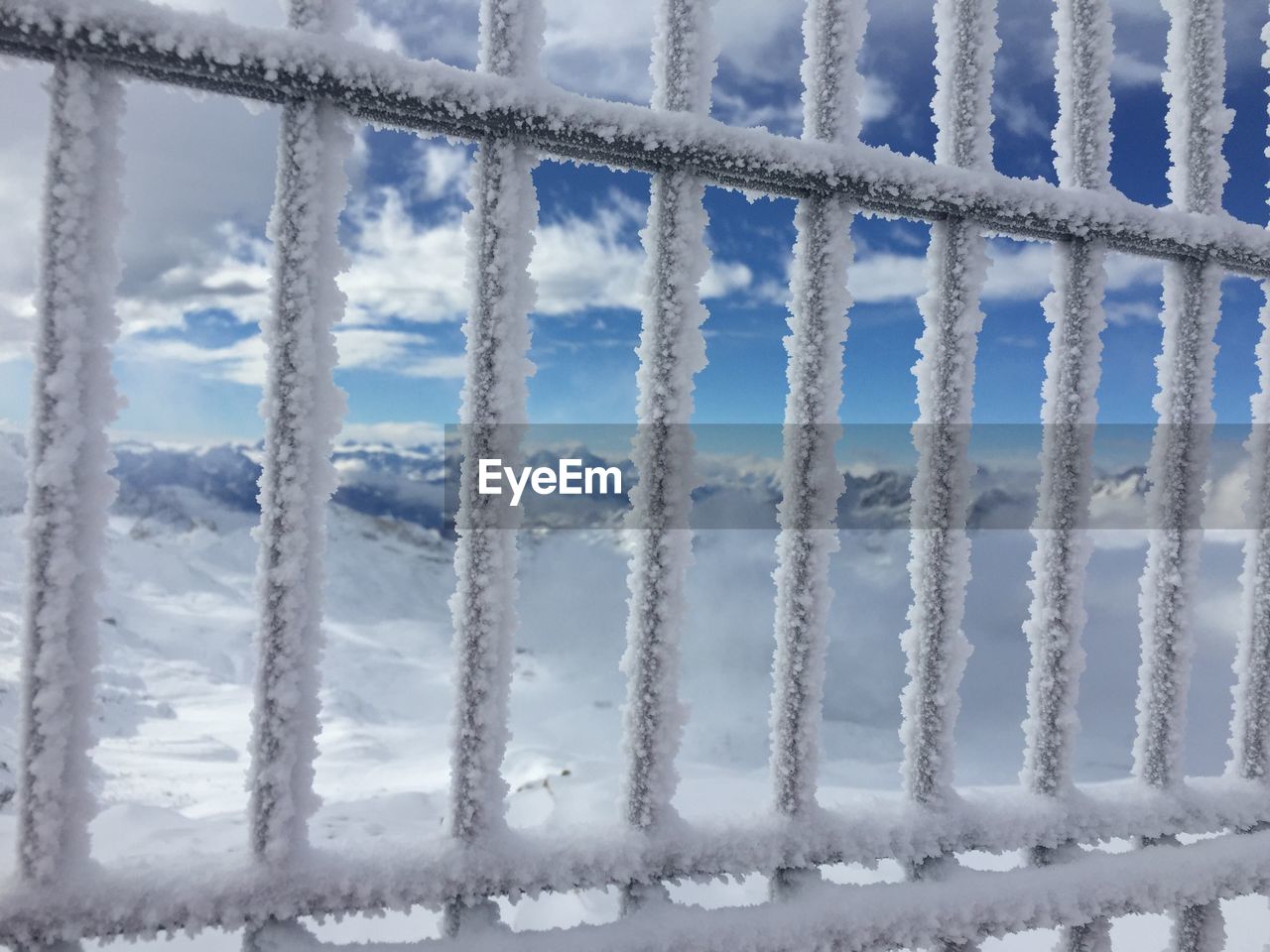 Close-up of frozen railing against sky