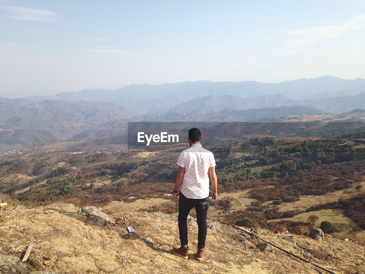 Rear view of man standing on mountain peak