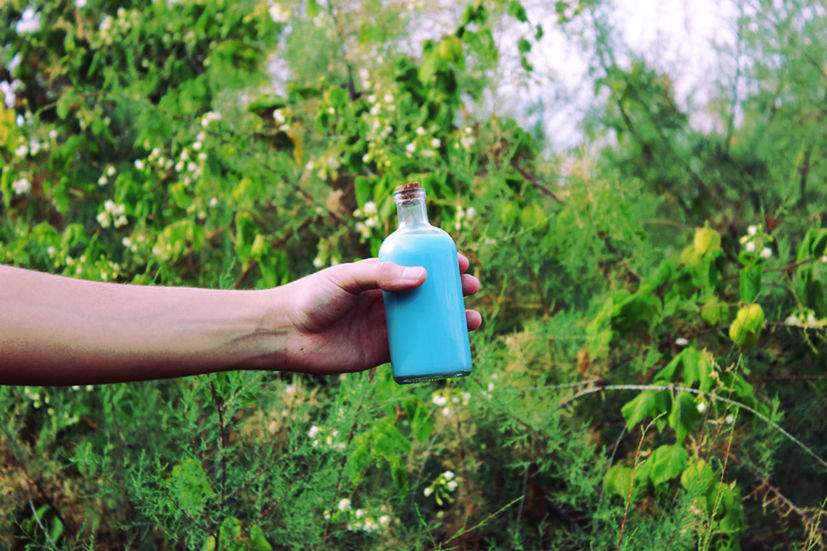 Cropped image of male hand holding bottle with blue liquid