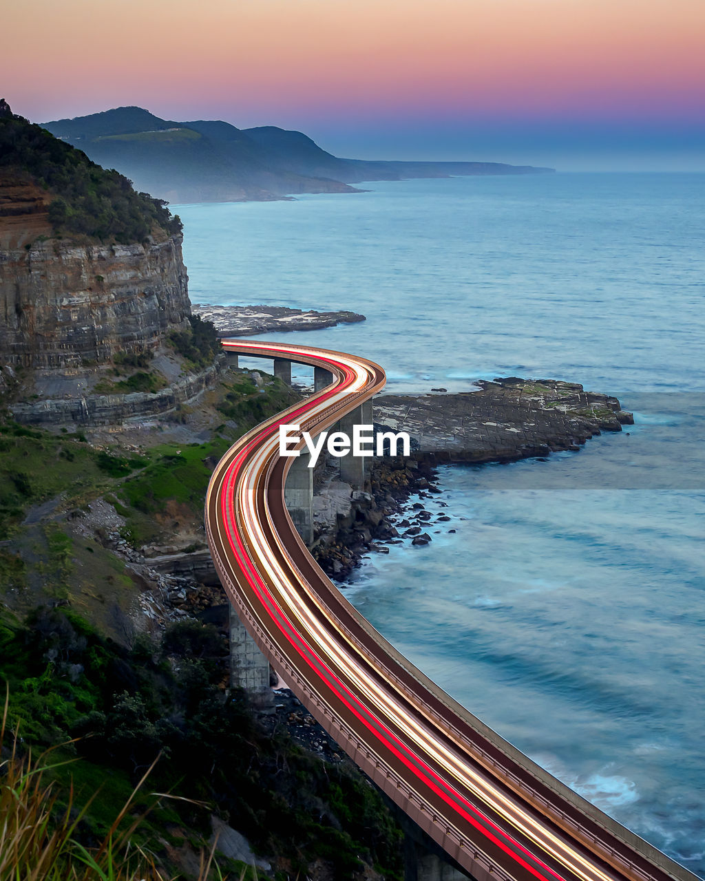 High angle view of light trails on bridge over sea during sunset