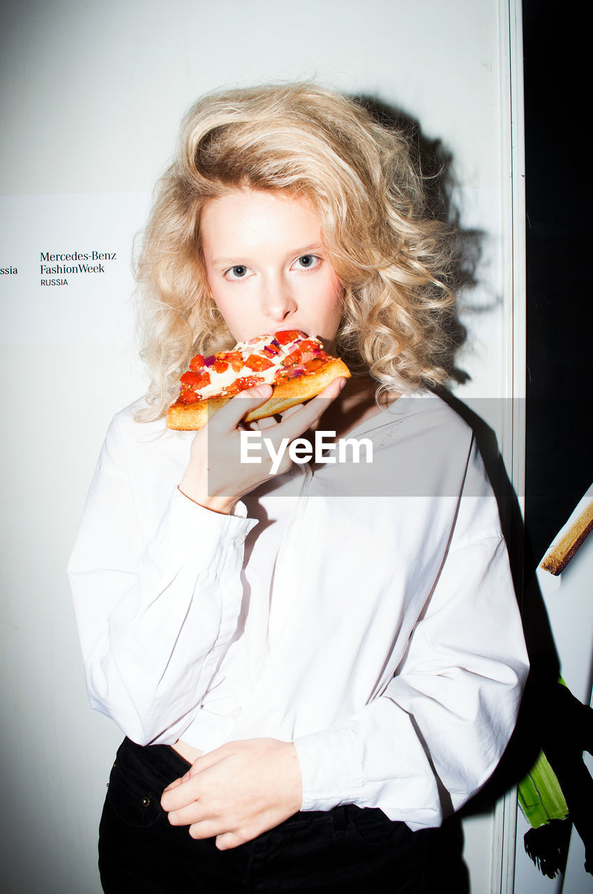 PORTRAIT OF YOUNG WOMAN HOLDING ICE CREAM IN KITCHEN