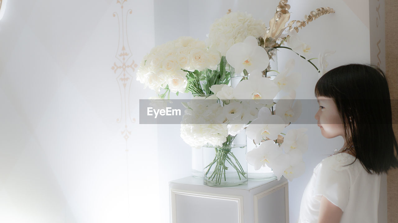 Girl standing by flowers in vase at home