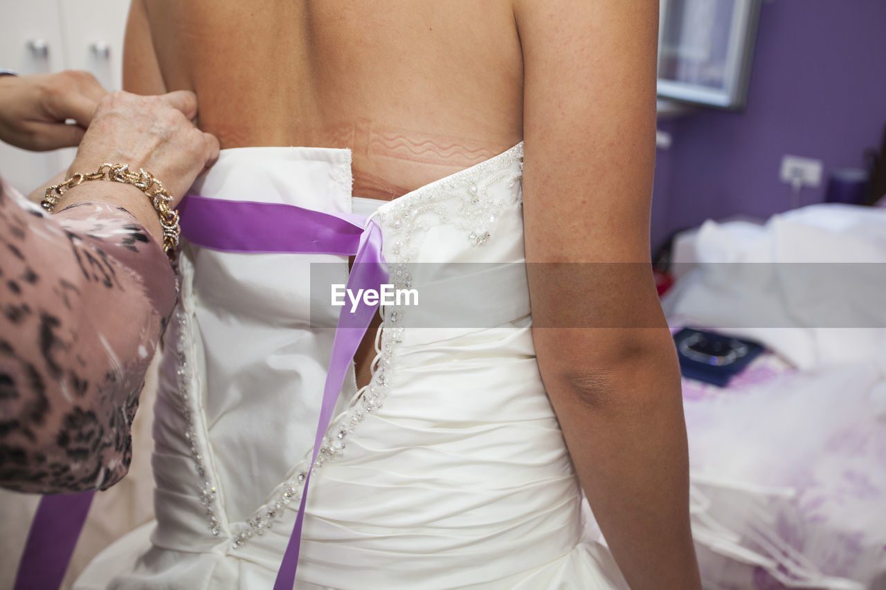 Cropped image of woman dressing bride