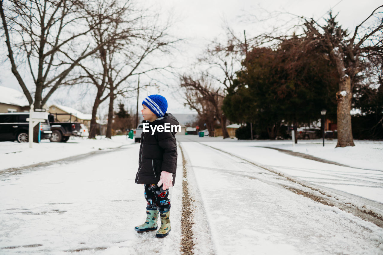 Young boy standing in snowy road wearing jacket in winter