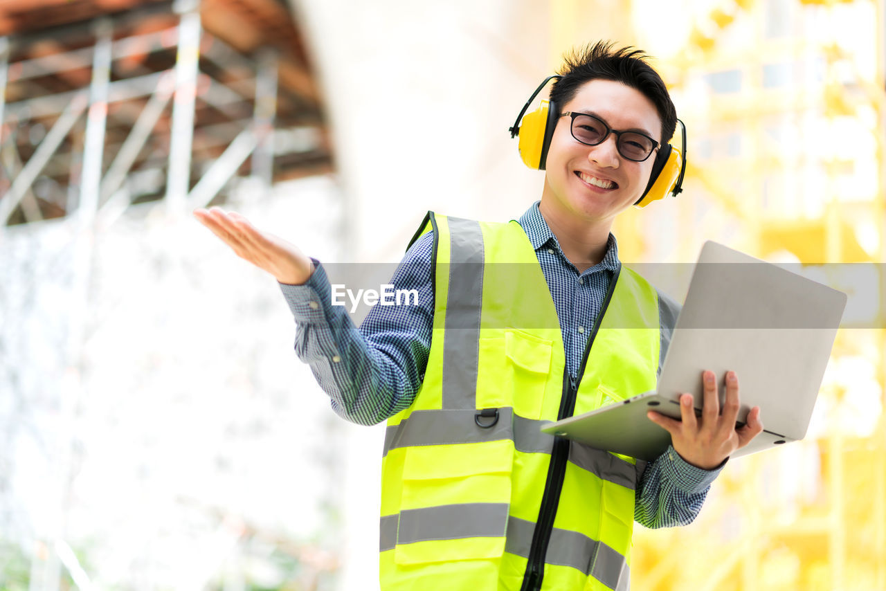 YOUNG MAN USING MOBILE PHONE WHILE STANDING ON CAMERA