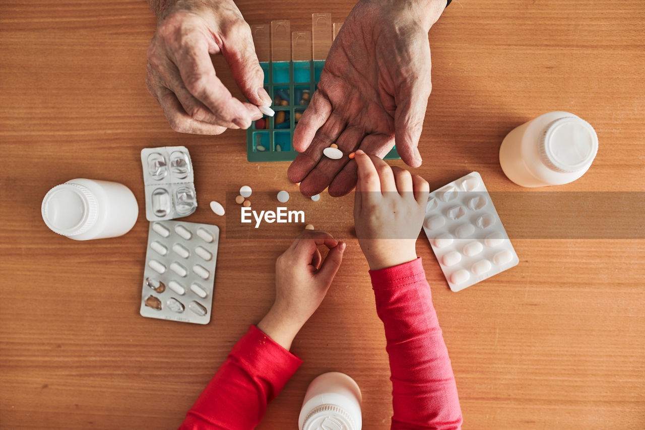 Grandchild helping grandfather to organize medication into pill dispenser. senior man routine