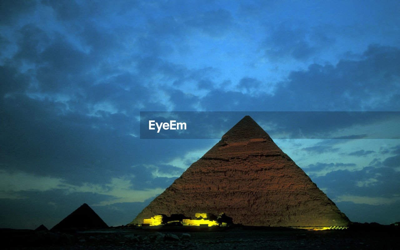 Old stone pyramids on desert landscape against sky