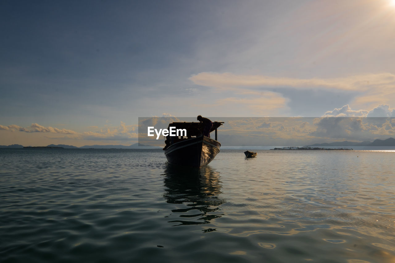 LONE BOAT IN CALM SEA AGAINST MOUNTAINS