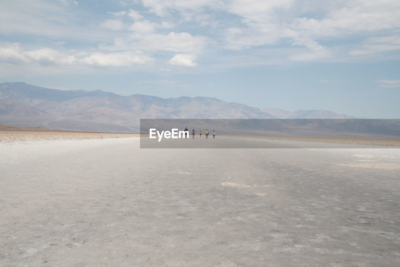 People walking on landscape against sky