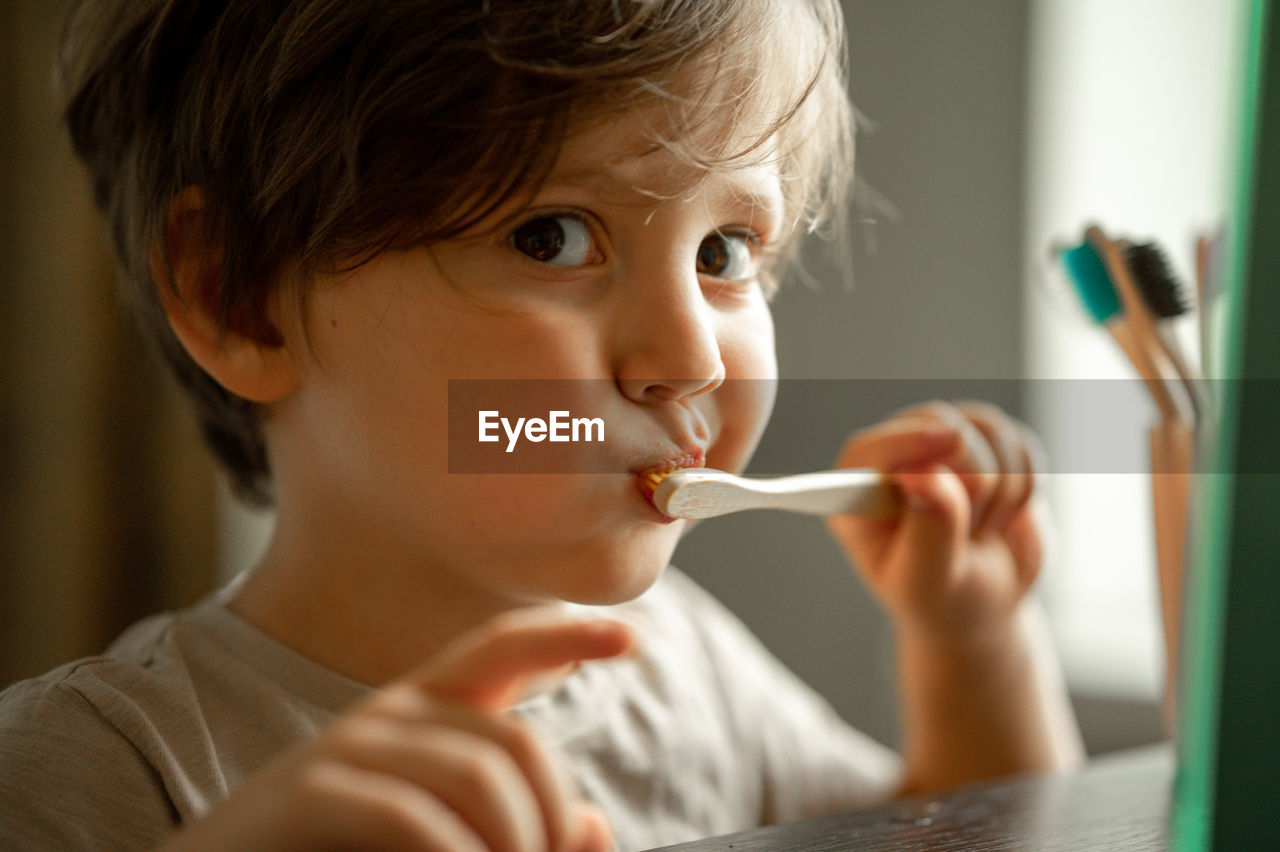 The boy brushes his teeth with a toothbrush made of ecological material