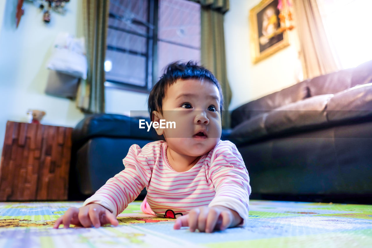 Close-up of cute baby girl lying at home