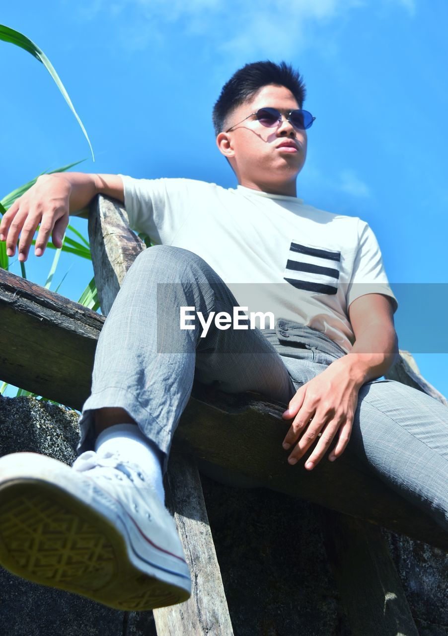 Low angle view of young man sitting outdoors