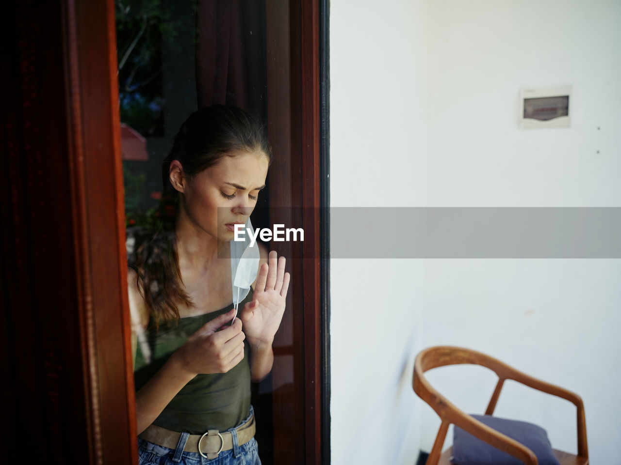 Young woman looking through window at door