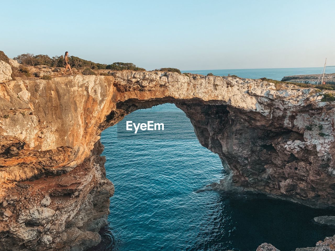 Rock formations by sea against clear sky