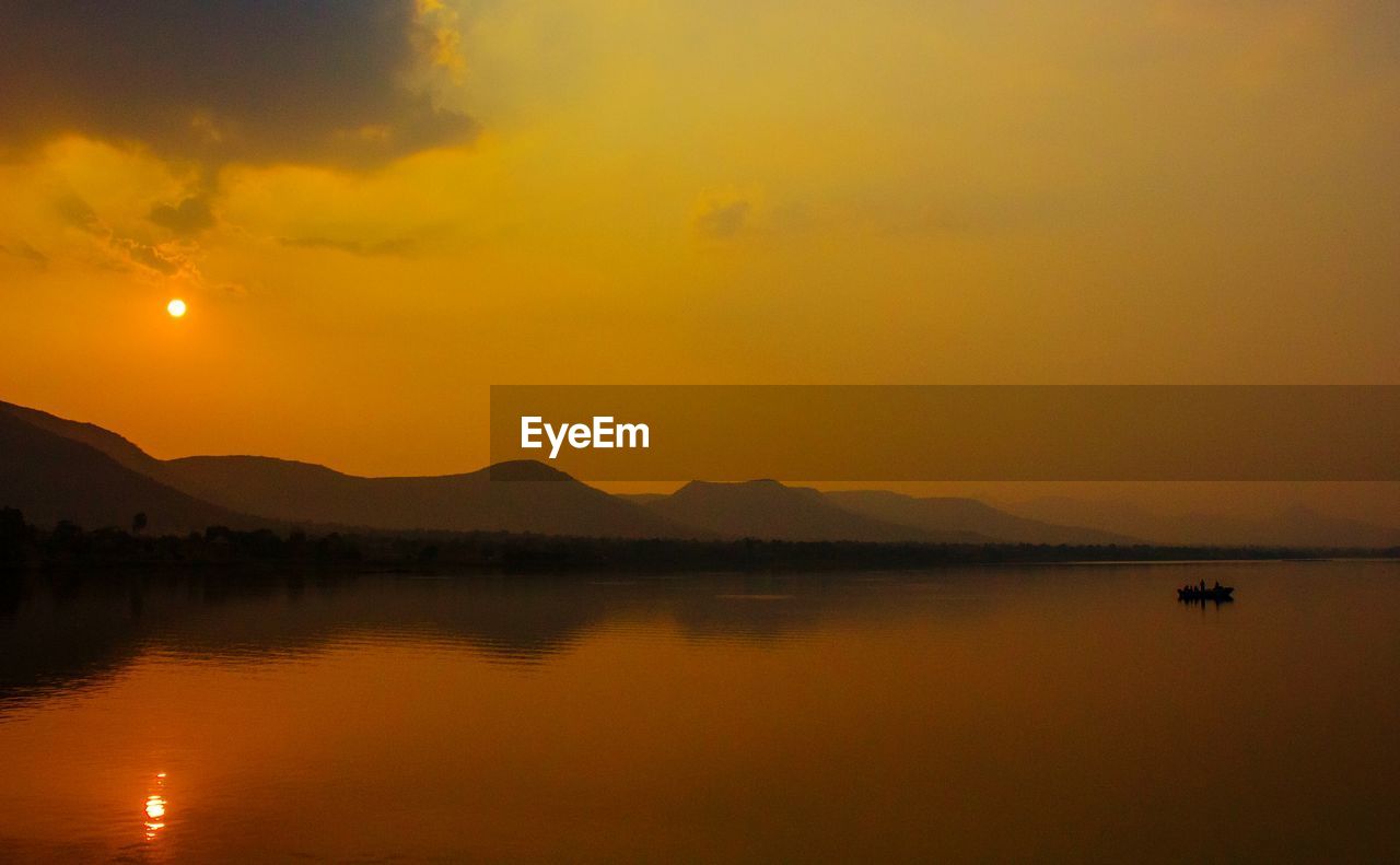 Scenic view of lake against orange sky