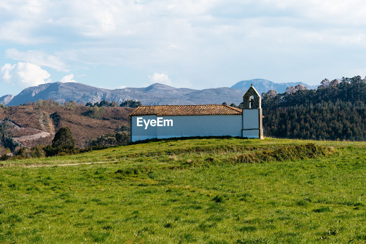 Small chapel in meadow against the mountains and blue sky, asturias. spain