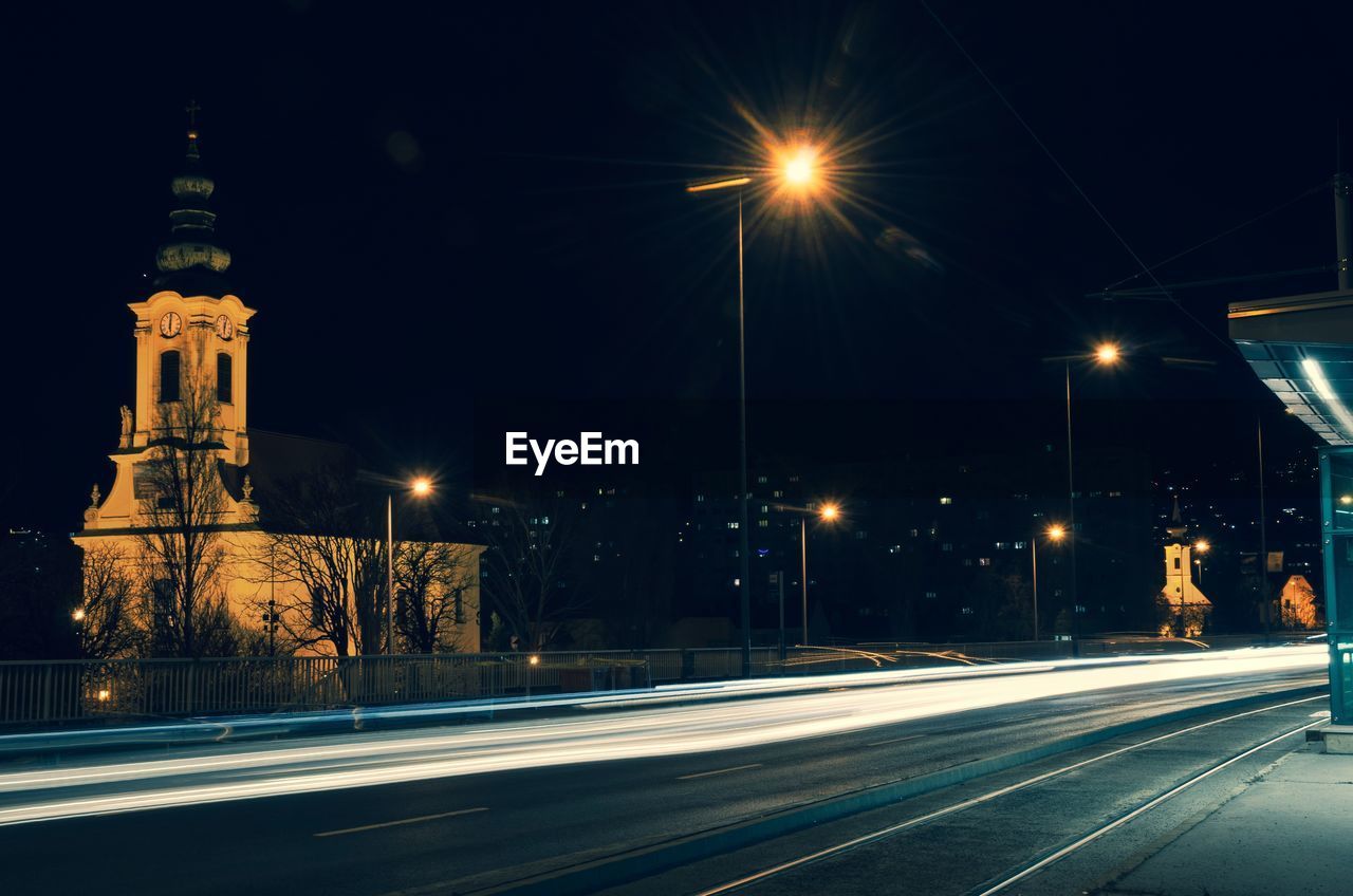 ILLUMINATED LIGHT TRAILS ON STREET AT NIGHT