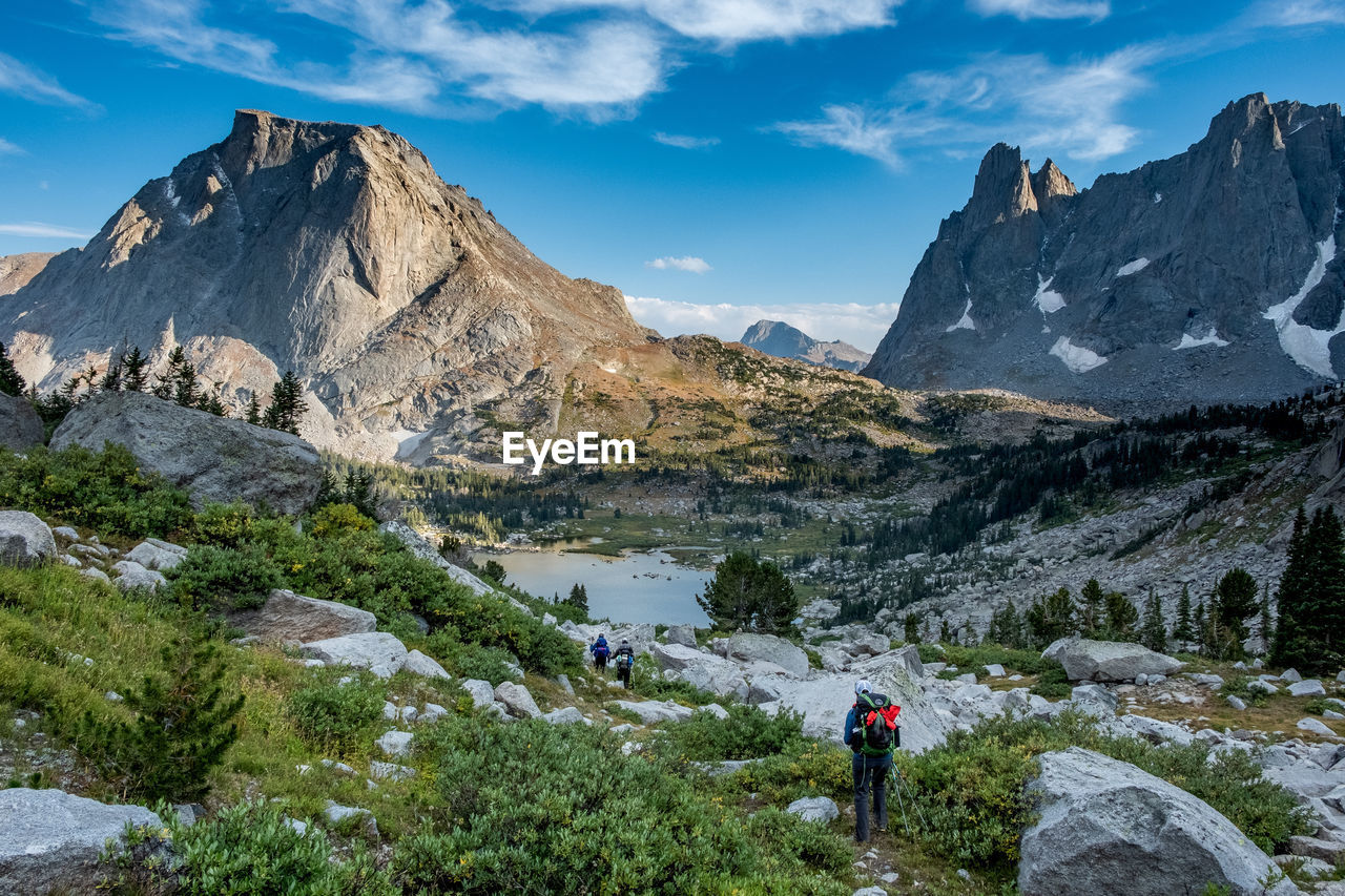 Woman walking on field against rocky mountains