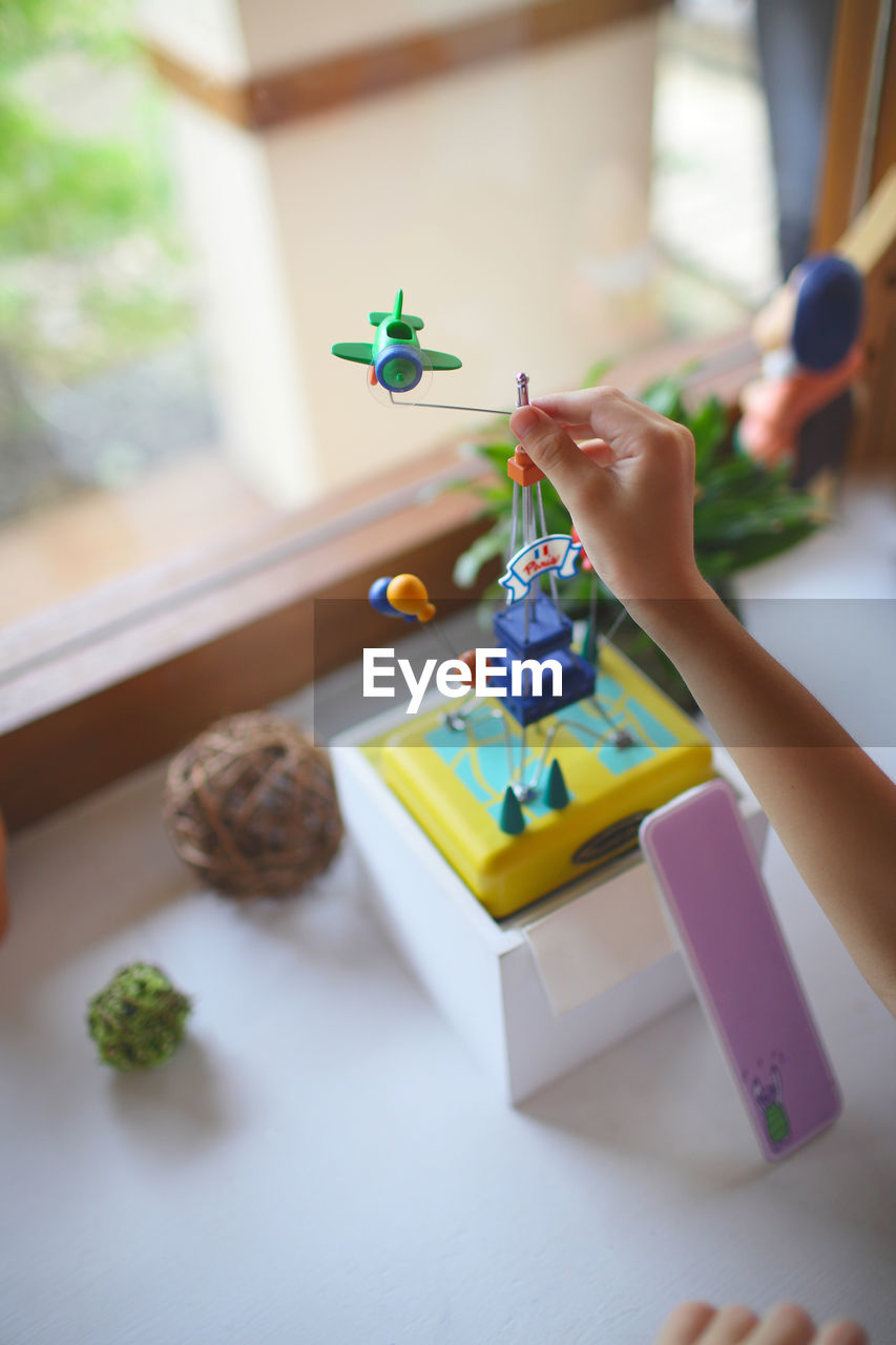 Boy playing with toy on table by window at home