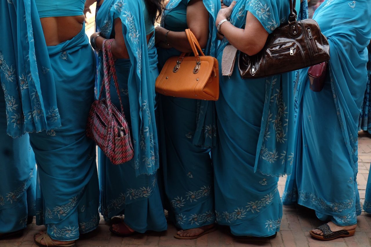 Low section of women in blue sari standing on footpath